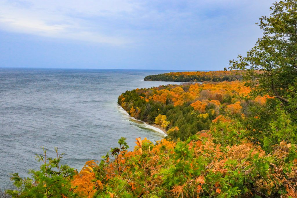 The curving coastline and colorful fall foliage viewed from a lookout point in Peninsula State Park in Door County, Wisconsin.