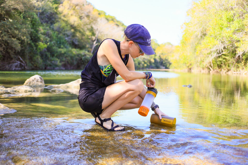 portable water filters that also purify: filling water bottle from a stream