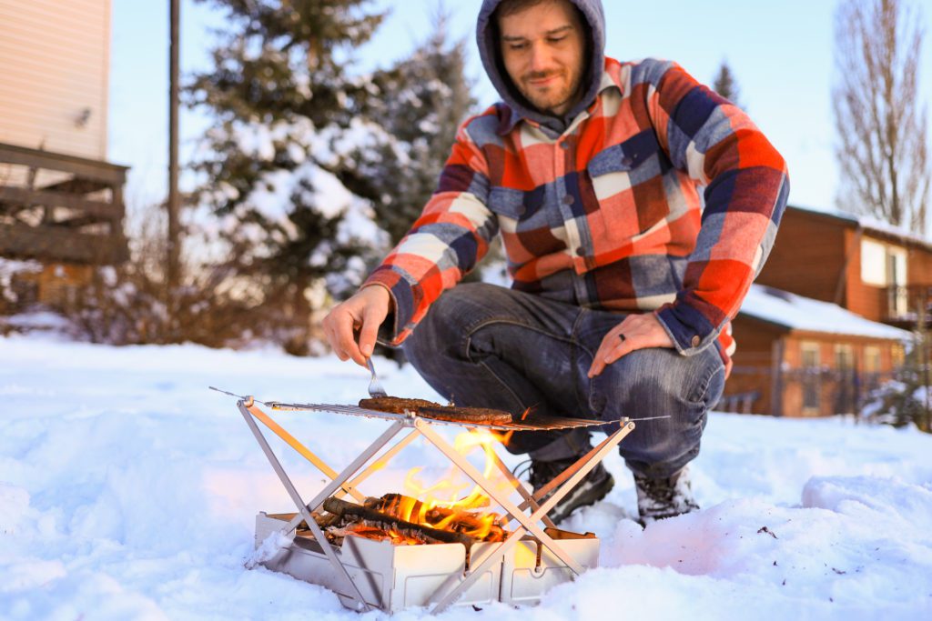 Josh cooking on the Wolf and Grizzly Fire Safe and Grill portable fire pit.