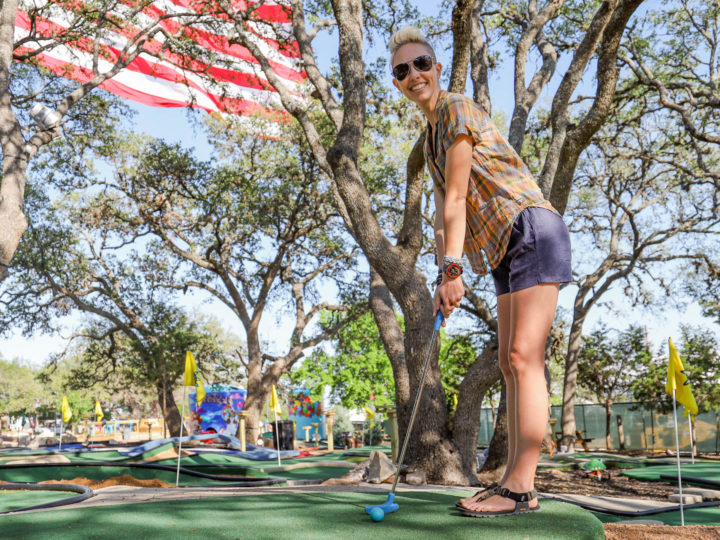 memorial day sales on outdoor gear: playing mini golf in front of a large American Flag