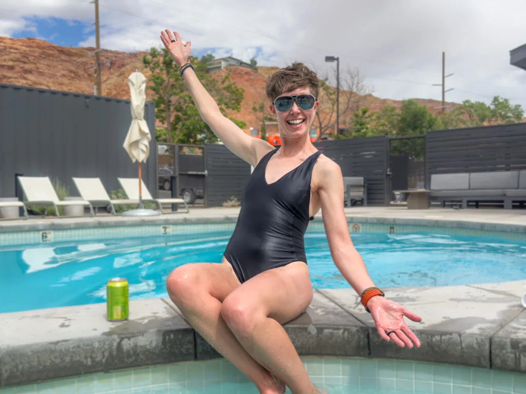 A woman sits beside a pool with the Carve Designs one piece swimsuit on.