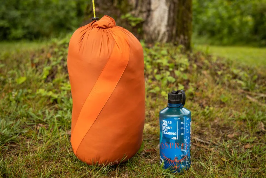 The Sierra Designs Night Cap 35 in its stuff sack (compared in size to a Nalgene).