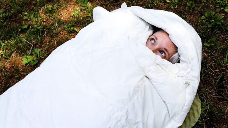 Just a woman's face peering out of a white Mountain Hardware Lamina Eco AF sleeping bag.