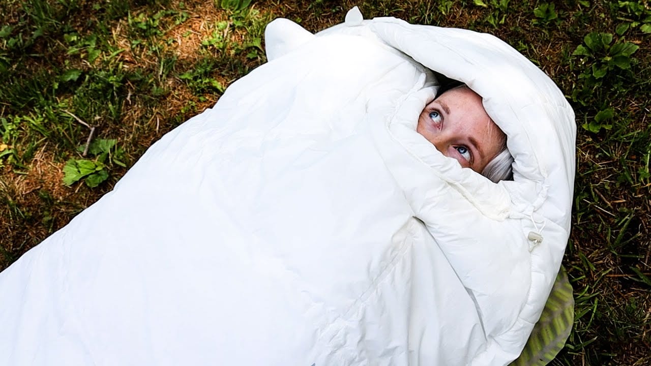 Just a woman's face peering out of a white Mountain Hardware Lamina Eco AF sleeping bag.