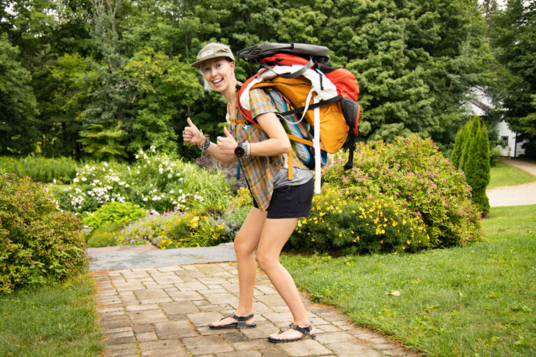 A woman carrying a stack of sustainable day packs