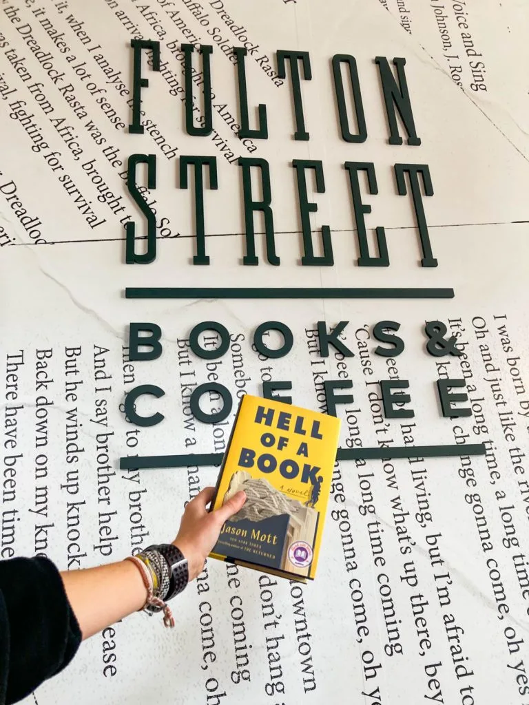 A book in front of the Fulton Street Books and Coffee sign.