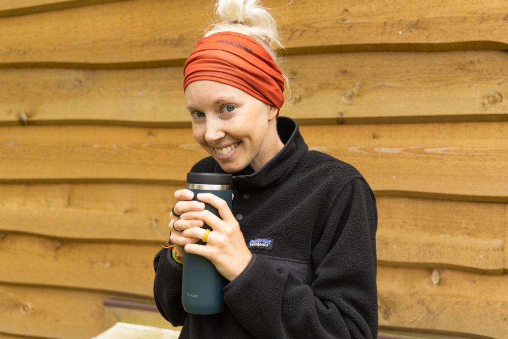A woman clutching a mug, dressed in the sustainable fleece Patagonia Synchilla Snap-T Pullover in black.