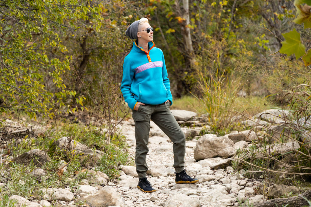 A woman in the Cotopaxi Teca Sustainable Fleece Pullover on a hiking trail.