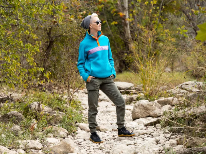 woman in a bright blue fleece on a hiking trail.