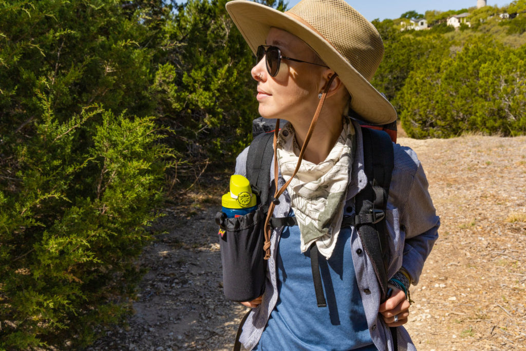 Woman hiking with a Waymark Gear Co. MILE 28 backpack with a Stretch Water Bottle pocket attachment. 