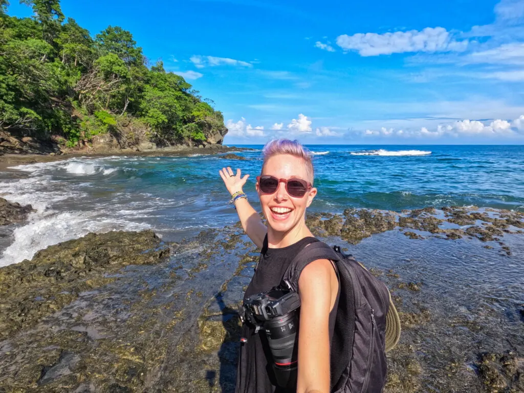 A woman gestures to a beach in Costa Rica.