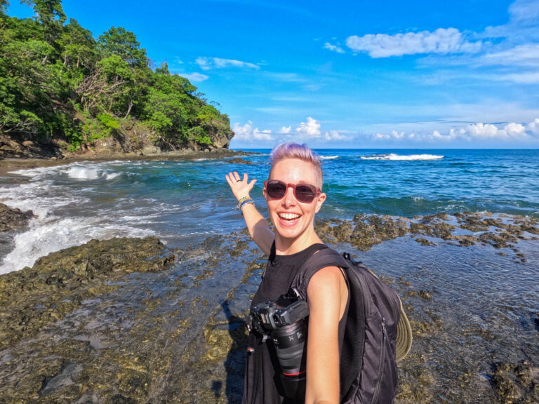 a woman gestures to the ocean in Costa Rica.