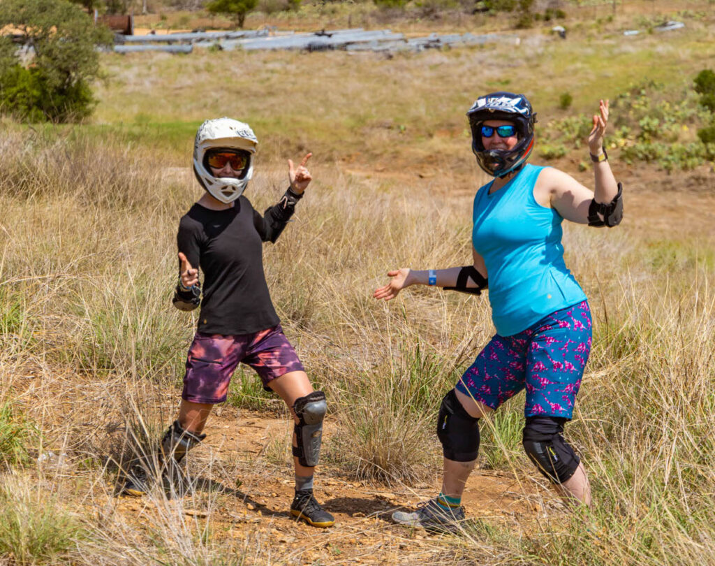 Two women pose in helmets and SHREDLY mountain bike apparel.