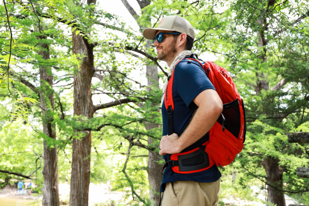 Backpack vs hip pack: a man in profile wears a daypack in the woods.