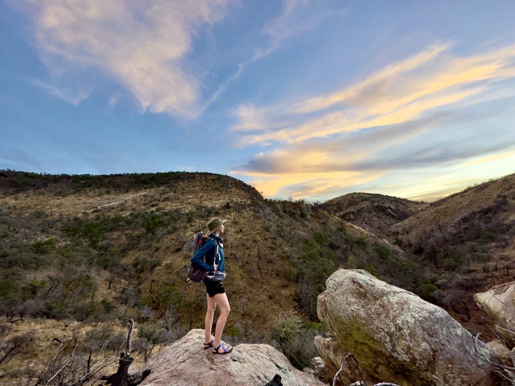 A woman backpacking looks at the sunset in Big Bend National Park.