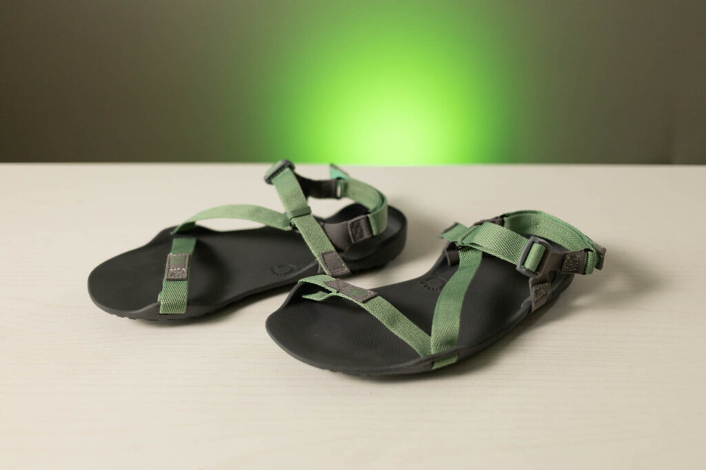 A pair of Xero Shoes Z-Trek sandals in green sit on a table.
