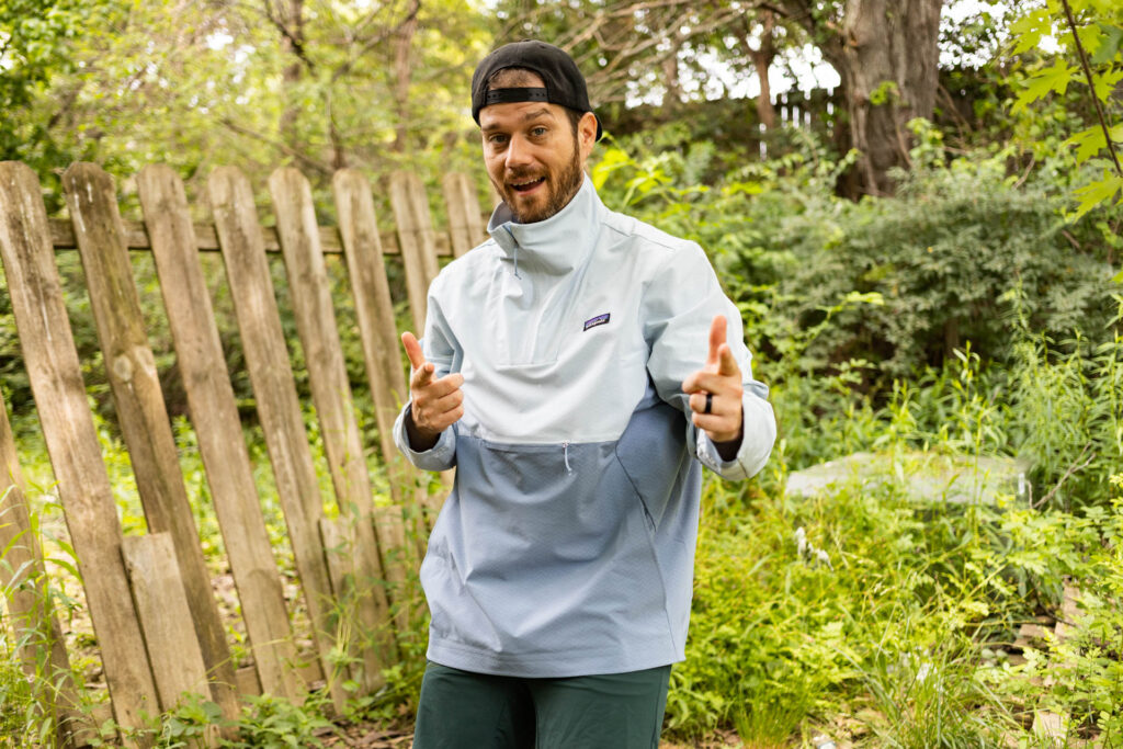 A man poses in a Patagonia CrossStrata Pullover jacket in light blue.