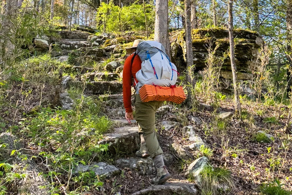A man hikes wearing an Osprey Levity backpack.