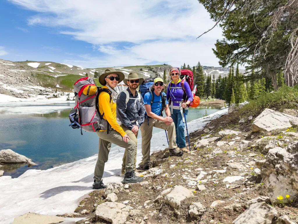 A family in front of a lake while backpacking in Grand Teton National Park.