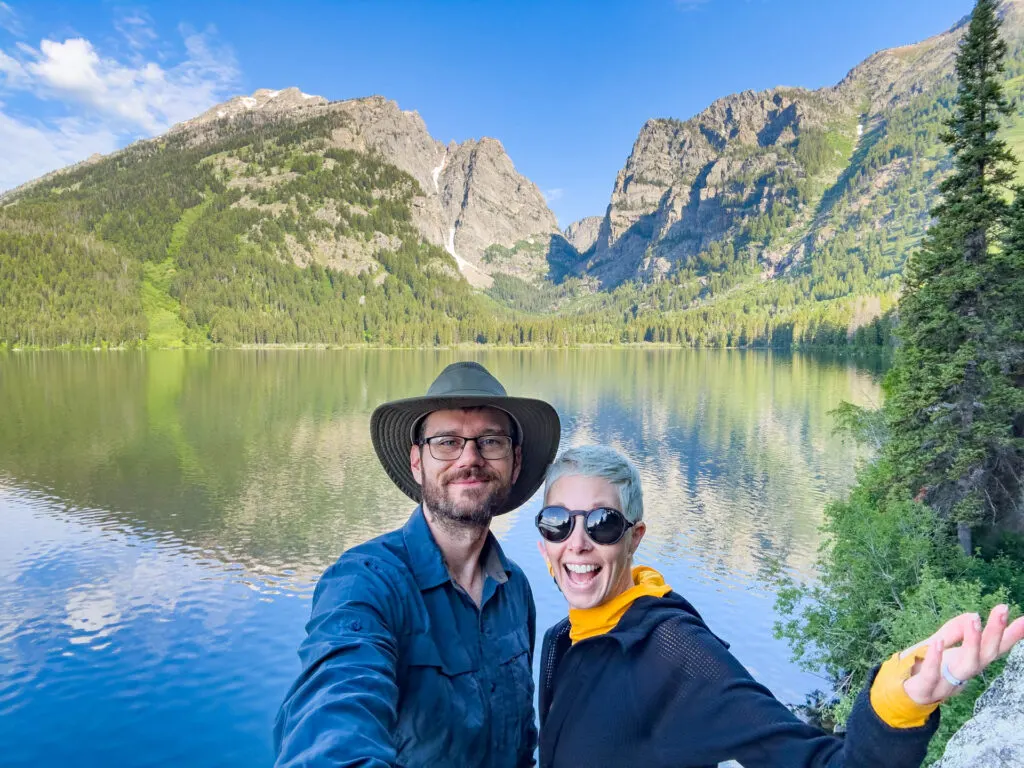 a man and woman smile next to Phelps Lake.