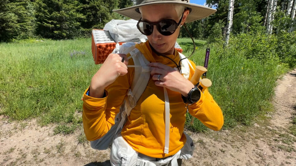 A woman adjusts a bungee cord on the pack straps of her Granite Gear Crown 3.