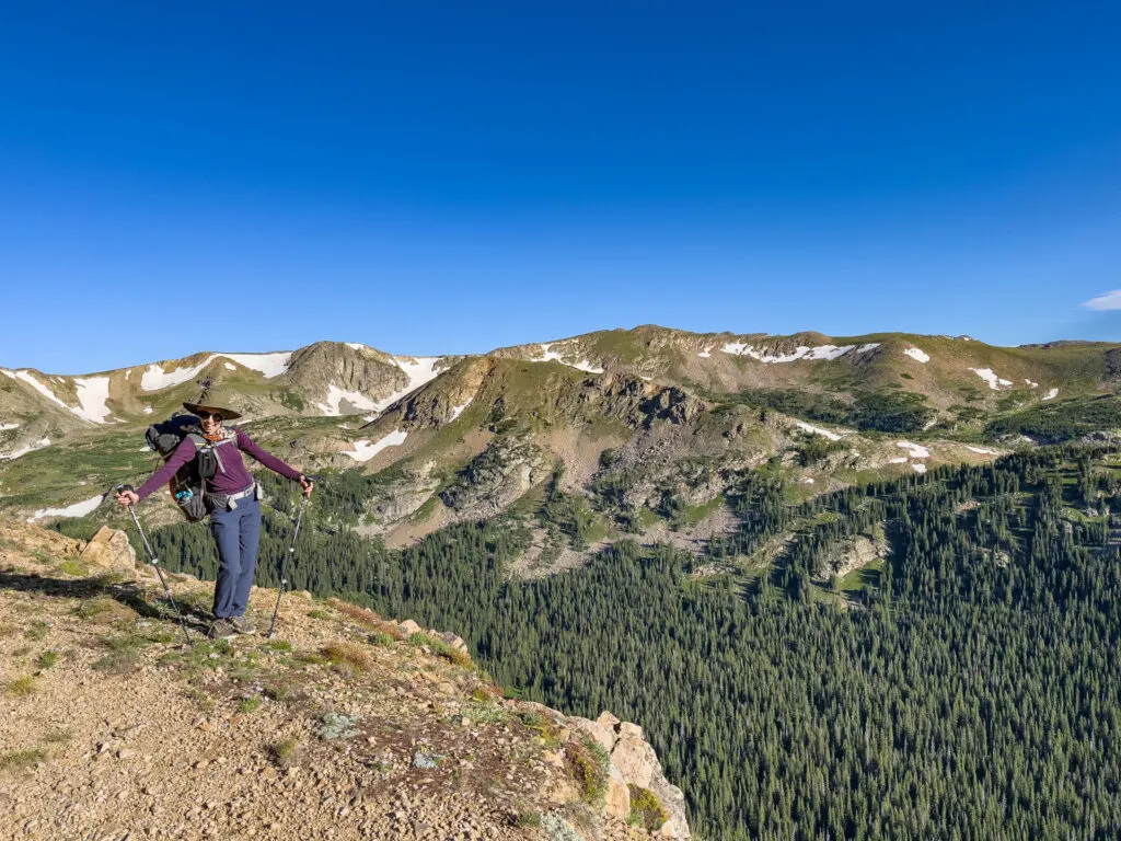 Backpacking in Colorado during the Fjallraven Classic USA: A woman does a silly pose in front of mountains.