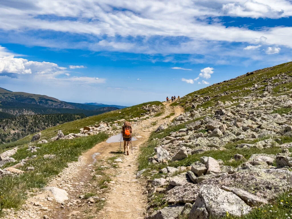 Backpacking in Colorado during The Fjallraven Classic USA: hikers trek up a trail with mountains in the background.