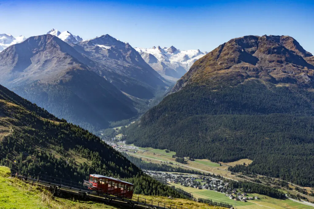 The Muottas Muragl funicular climbs up the mountain with more mountains and the valley in the background.