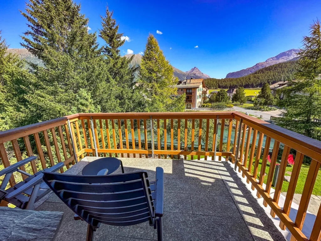 The view of pine trees, mountains, a river and Swiss architecture from our balcony at Chesa Rosatch.