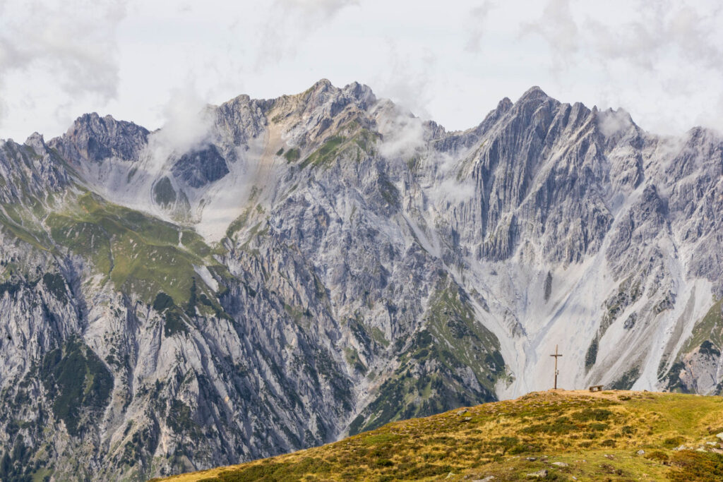 A cross in front of mountains on the Arlberg Trail in Austria.