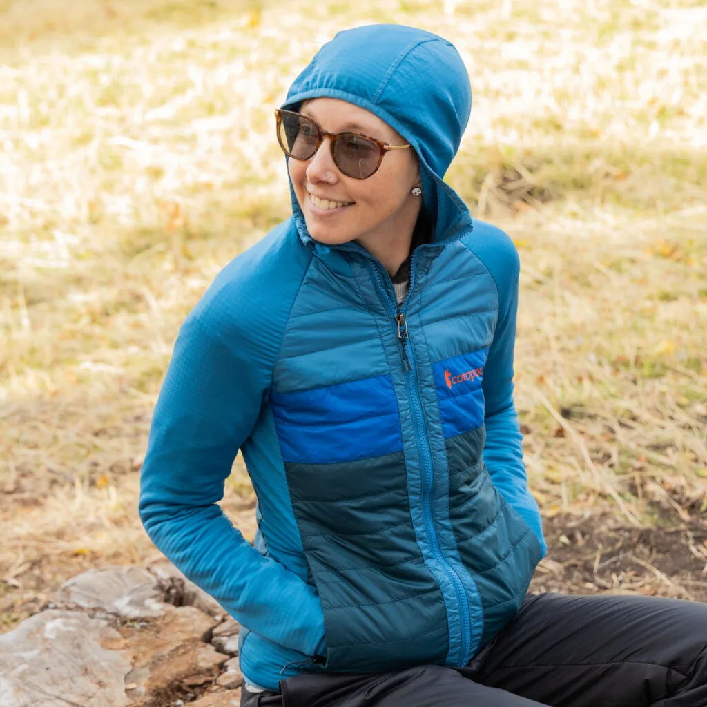 A woman wears the Cotopaxi Capa Hybrid Insulated Hooded Jacket.