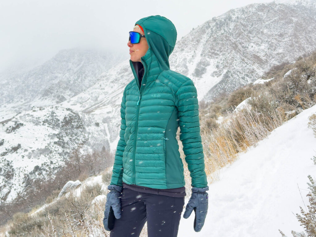 A woman in the The Rab Cirrus hybrid hoodie on a snowy mountain.