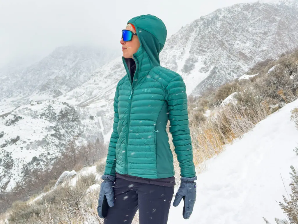 A woman in the The Rab Cirrus hybrid hoodie on a snowy mountain.