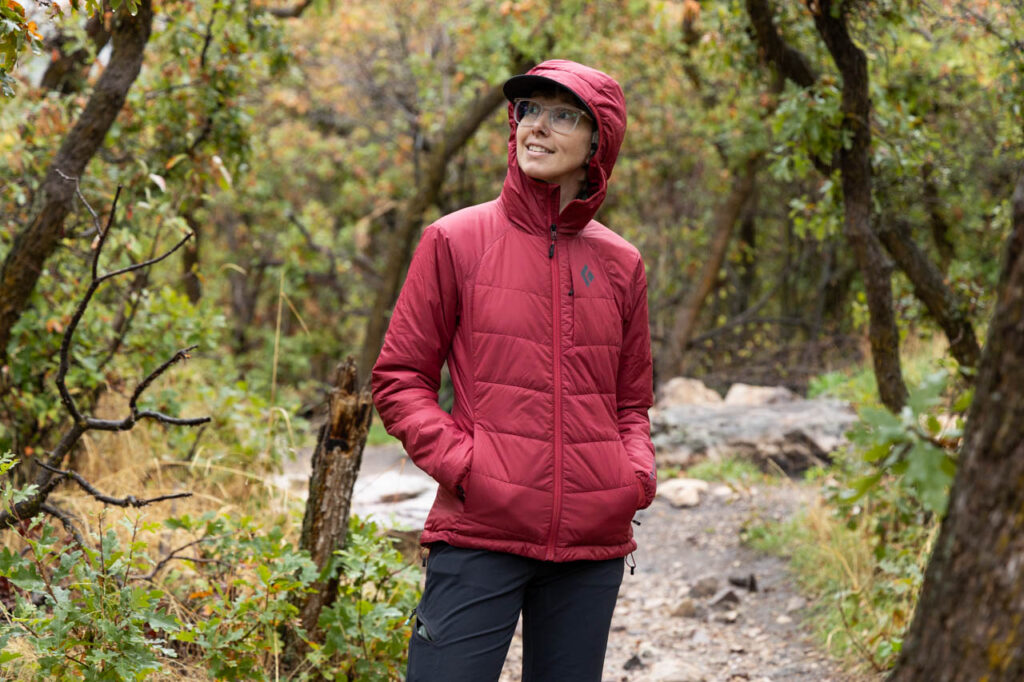 A woman stands on a trail wearing a Black Diamond Solution 2.0 Jacket.
