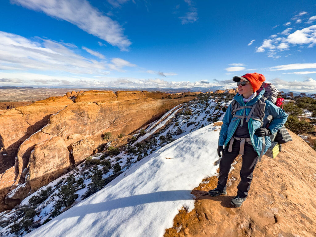 A woman in backpacking gear admires the view at Arches.