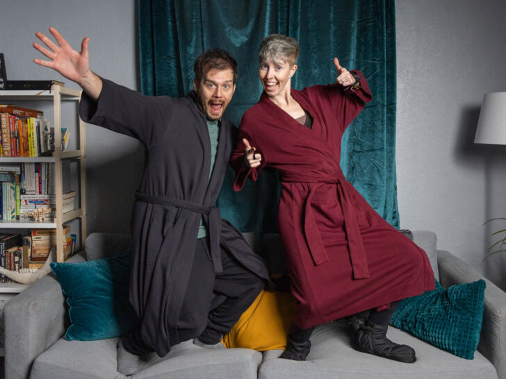 A man and woman stand on a couch in a silly pose wearing Subset organic cotton robes.