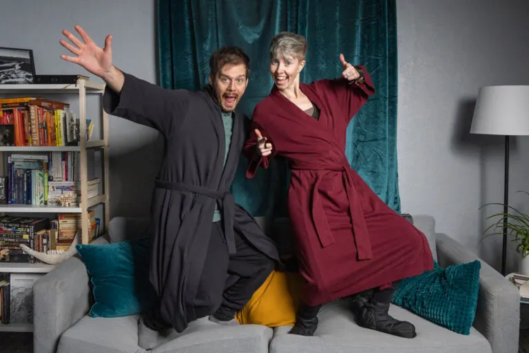 A man and woman stand on a couch in a silly pose wearing Subset organic cotton robes.
