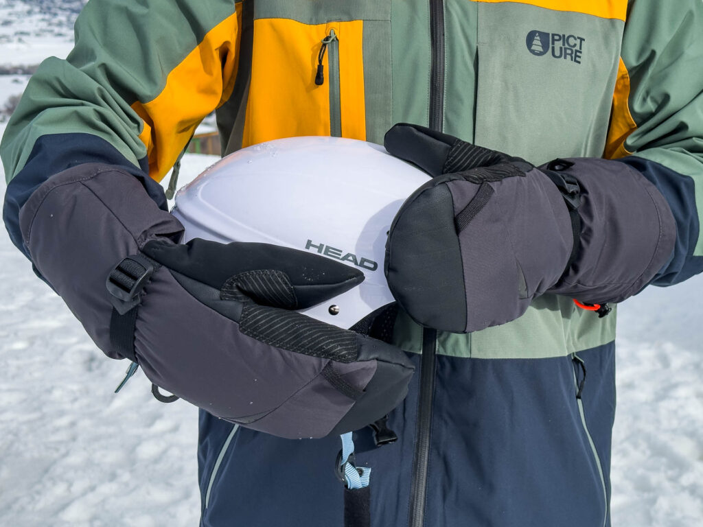 Holding a snowboard helmet while wearing the Jack Wolfskin Alpspitze 3-in-1 sustainable winter Gloves.