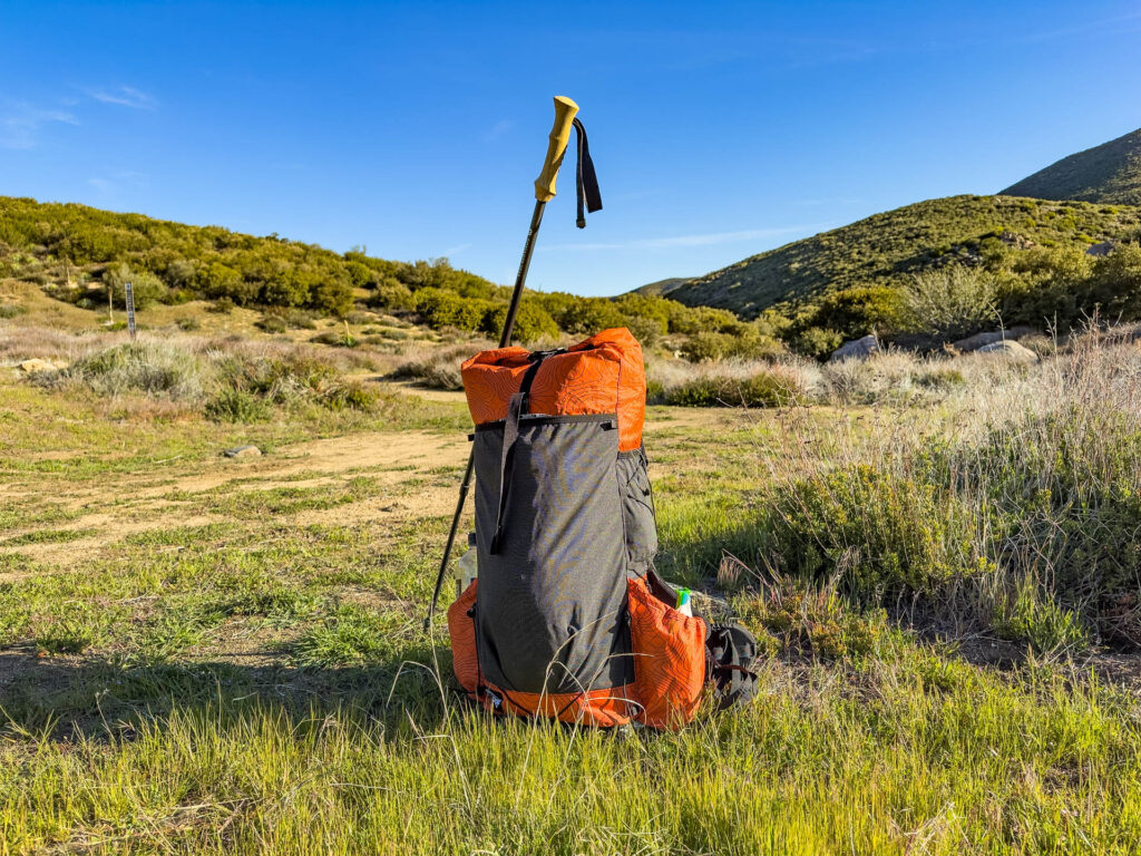 Lite AF backpack leaning on a trekking pole outside.