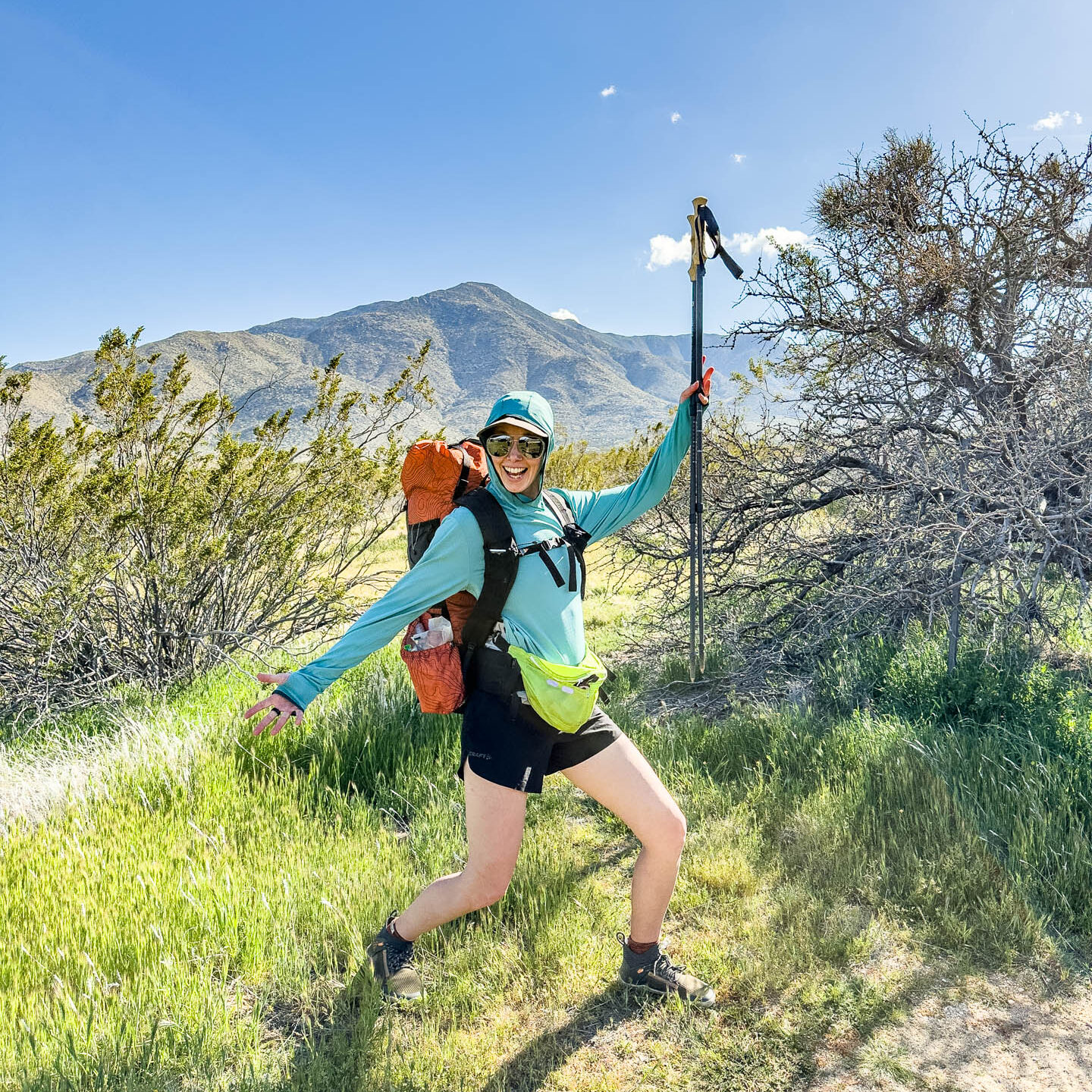 A happy hiker holds up trekking poles.