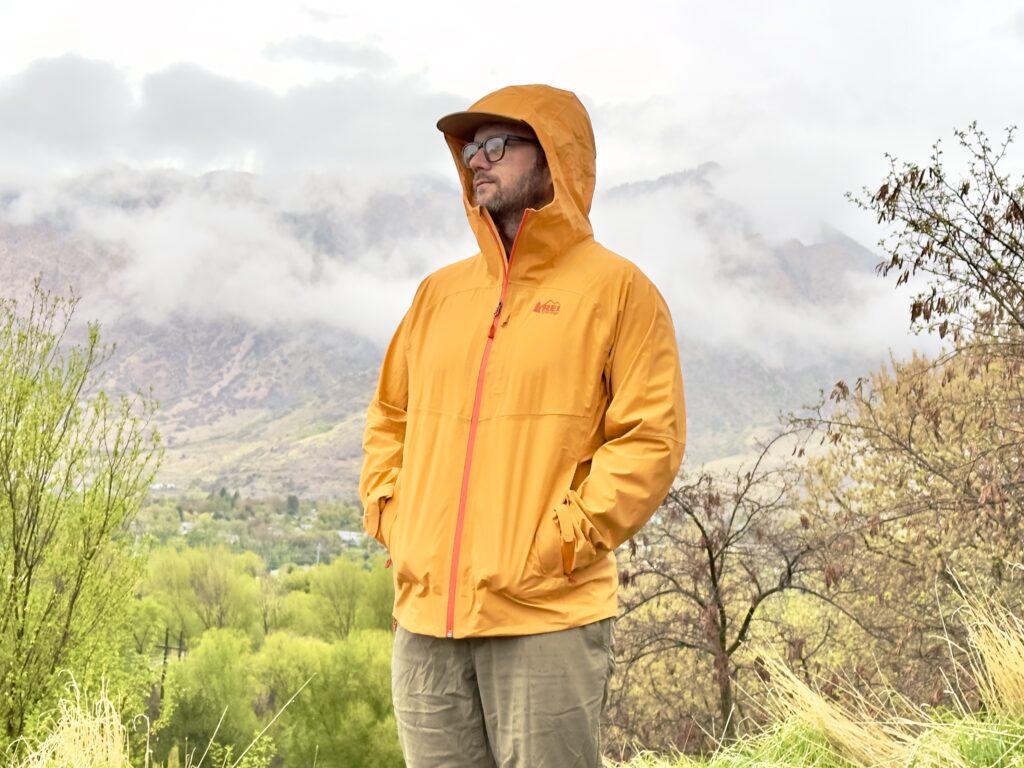 A man wears the REI Co-Op XeroCloud Rain Jacket in damp weather.
