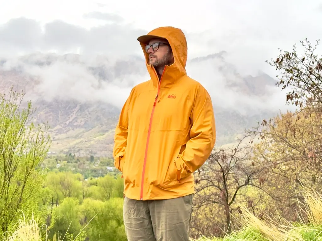 A man wears the REI Co-Op XeroCloud Rain Jacket in damp weather.