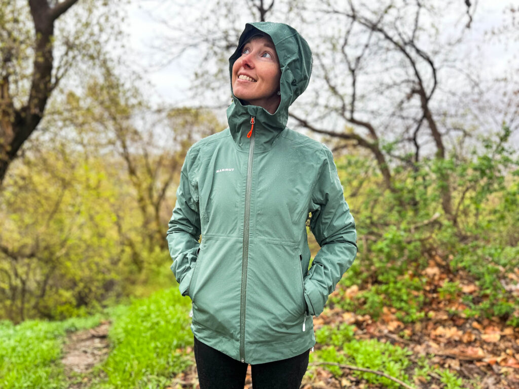A woman stands in the rain in The Mammut Alto Light Jacket.