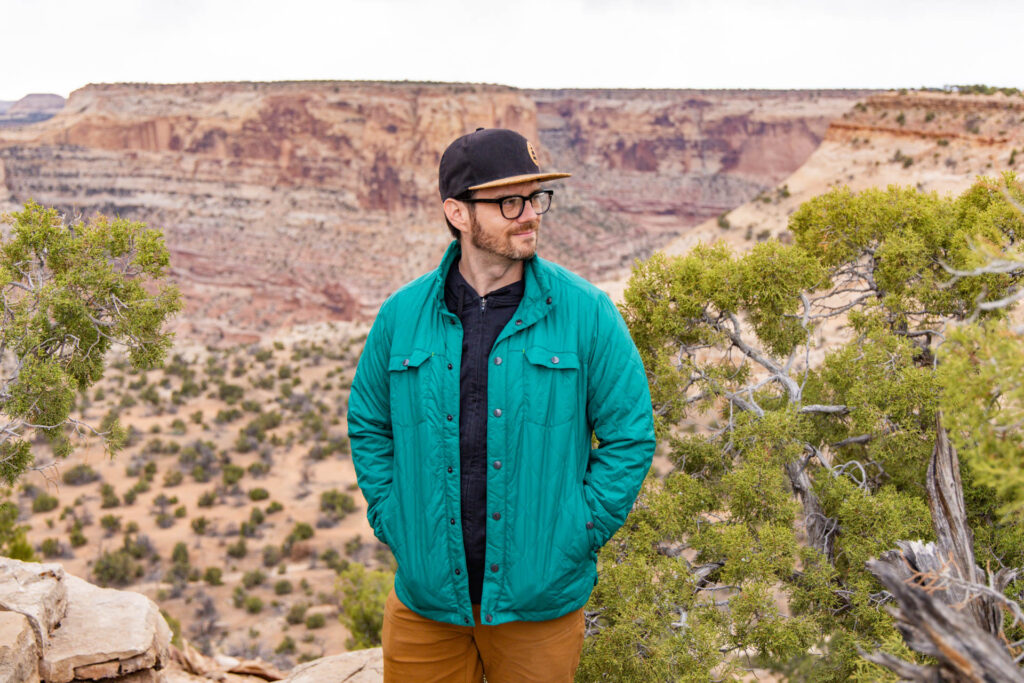 A man in a jacket smiles in front of a canyon.