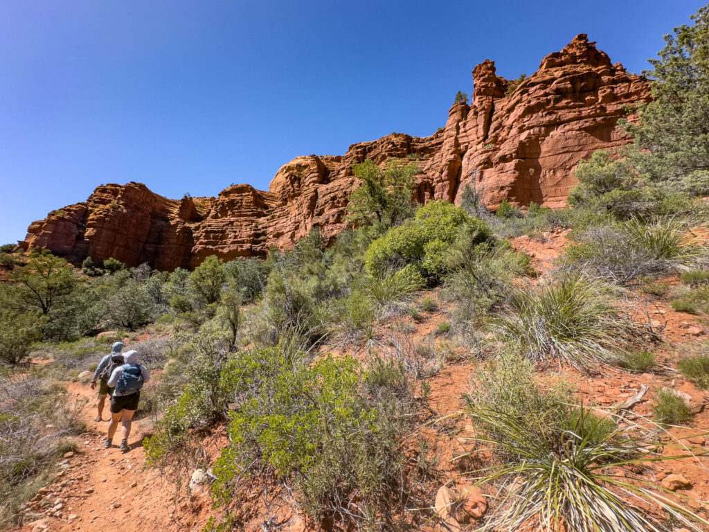 Hikers on a trail near large rock structures in Sedona on an REI Adventures Trip.