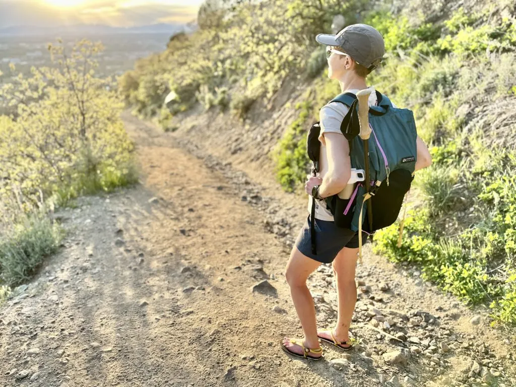 A woman on a trail takes in the view while wearing the Gossamer Gear Loris 25 daypack.