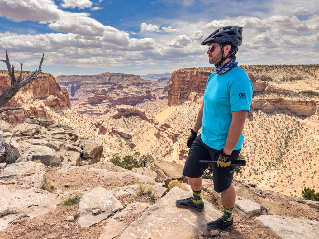 A man stands in front of Little Grand Canyon in Utah in bike clothing.