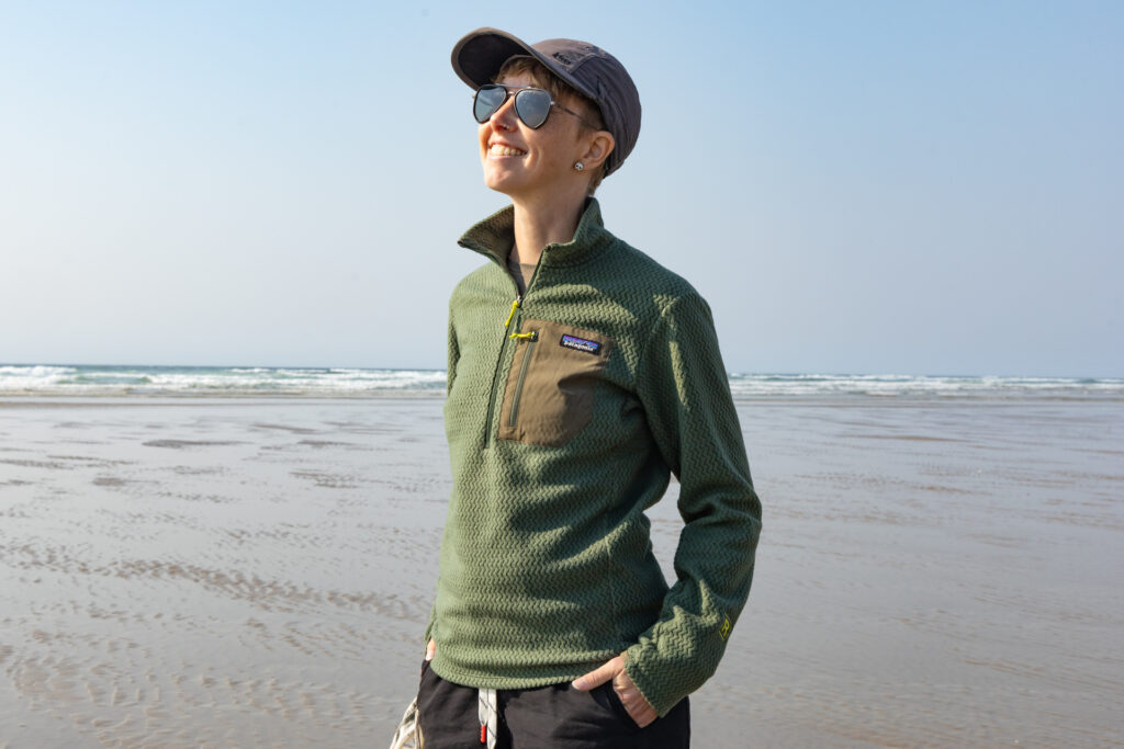 A woman on the beach wears a Patagonia R1 Air Zip Neck.