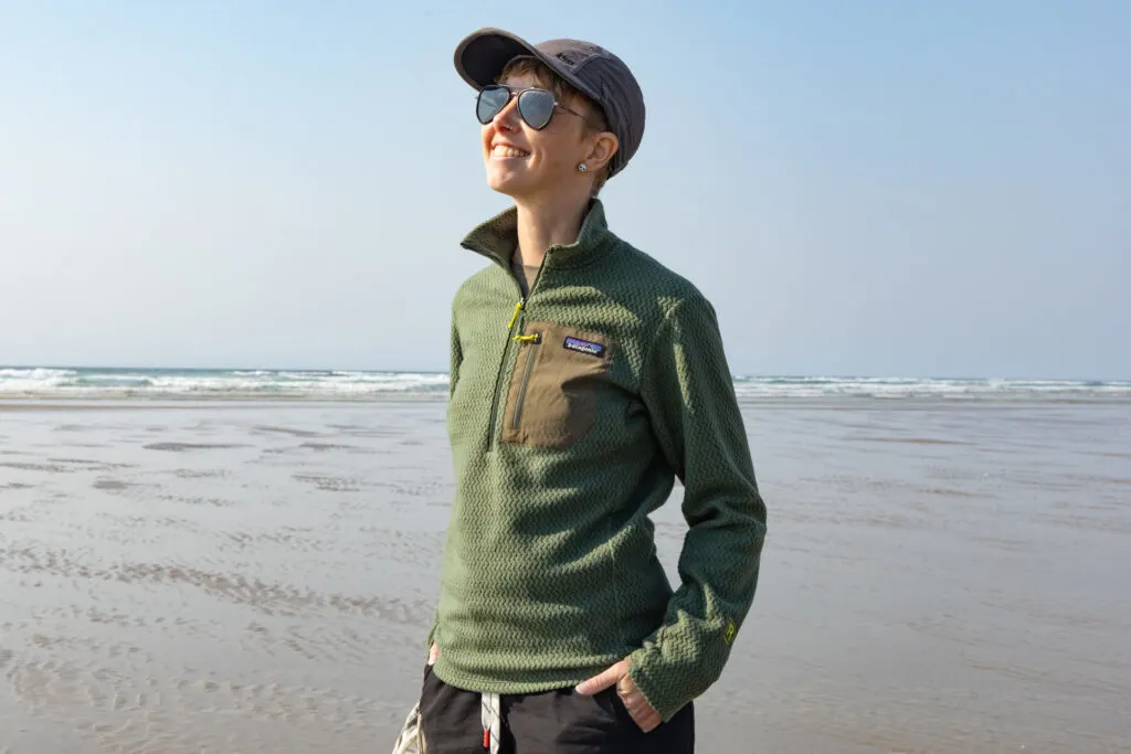 A woman on the beach wears a Patagonia R1 Air Zip Neck.