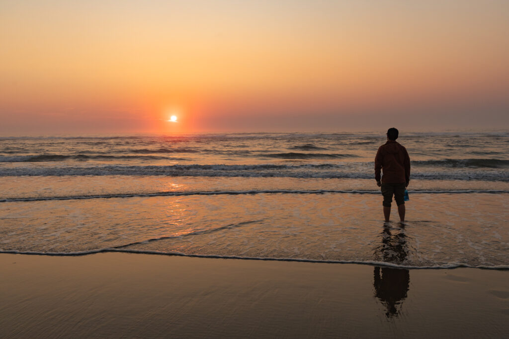 A man Standing on Haceta Beach in Oregon at sunset.